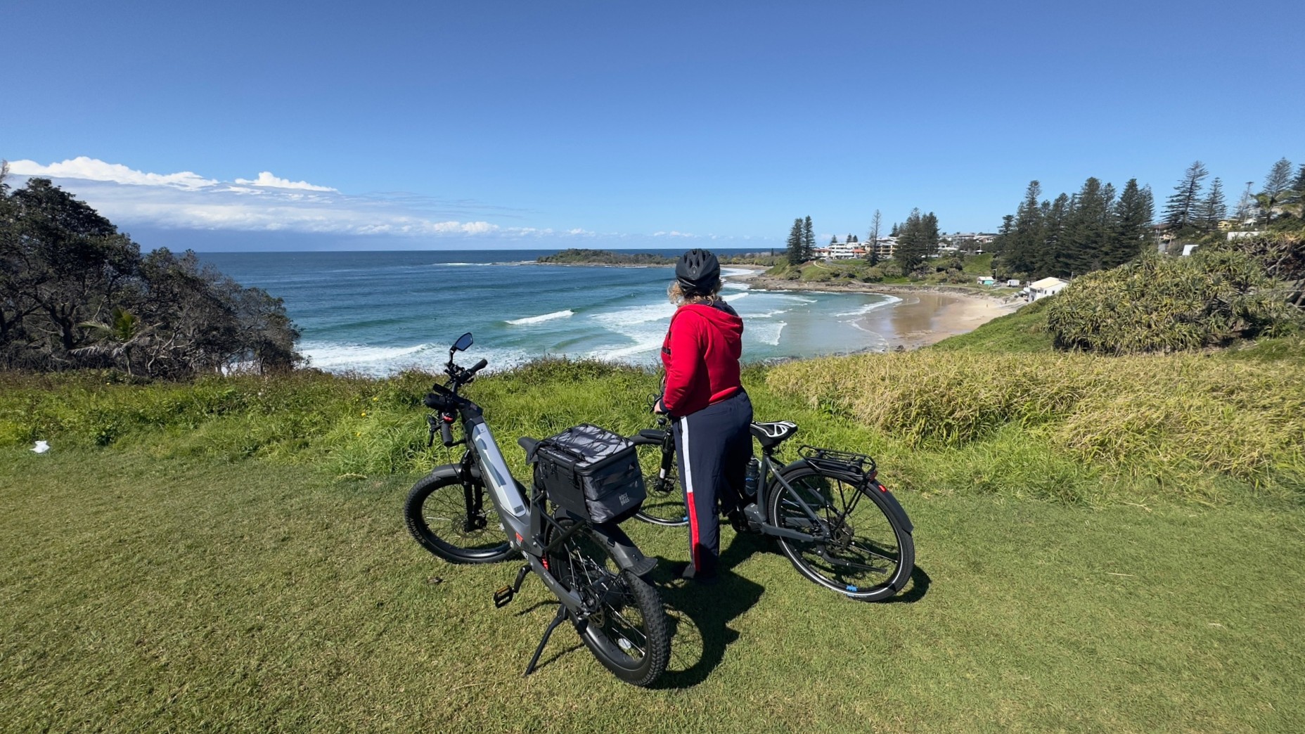 lady in red jacket with bicycle looking over beach in yamba nsw