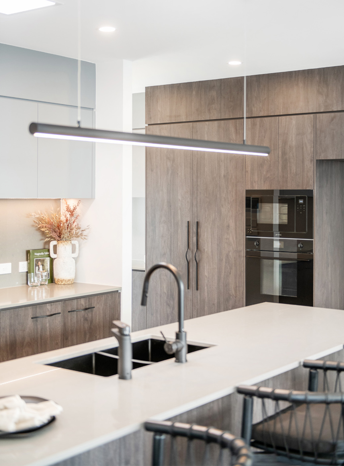 portrait image of a kitchen with overhead lighting, chrome tapware, professionally styled